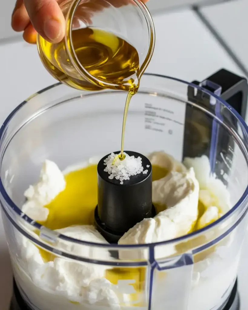 Adding olive oil and salt to ricotta before processing