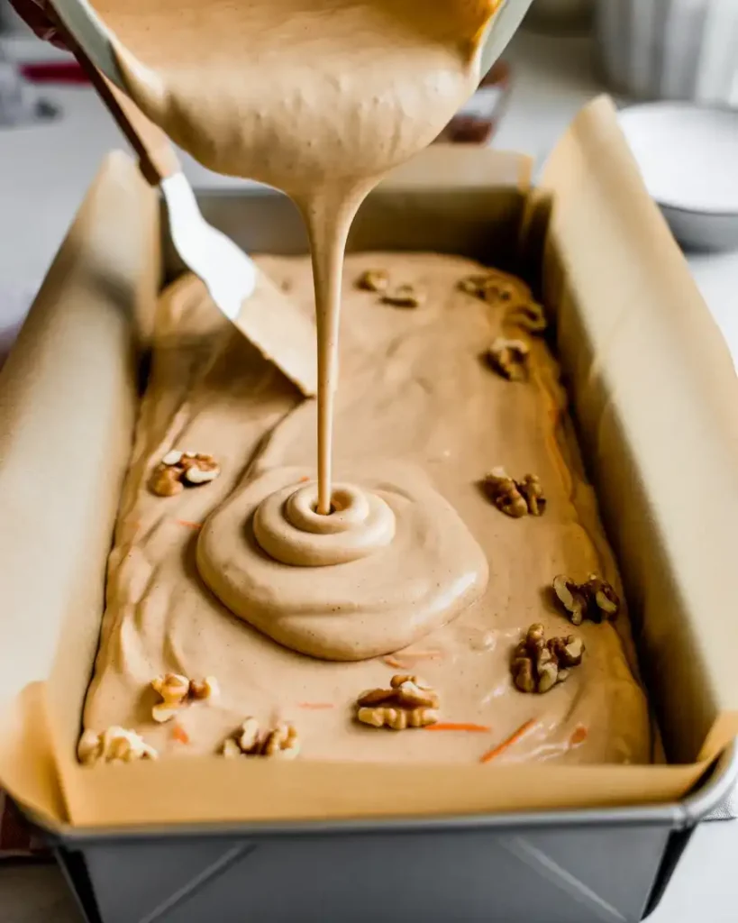 Spreading carrot cake batter evenly in a parchment-lined jelly roll pan
