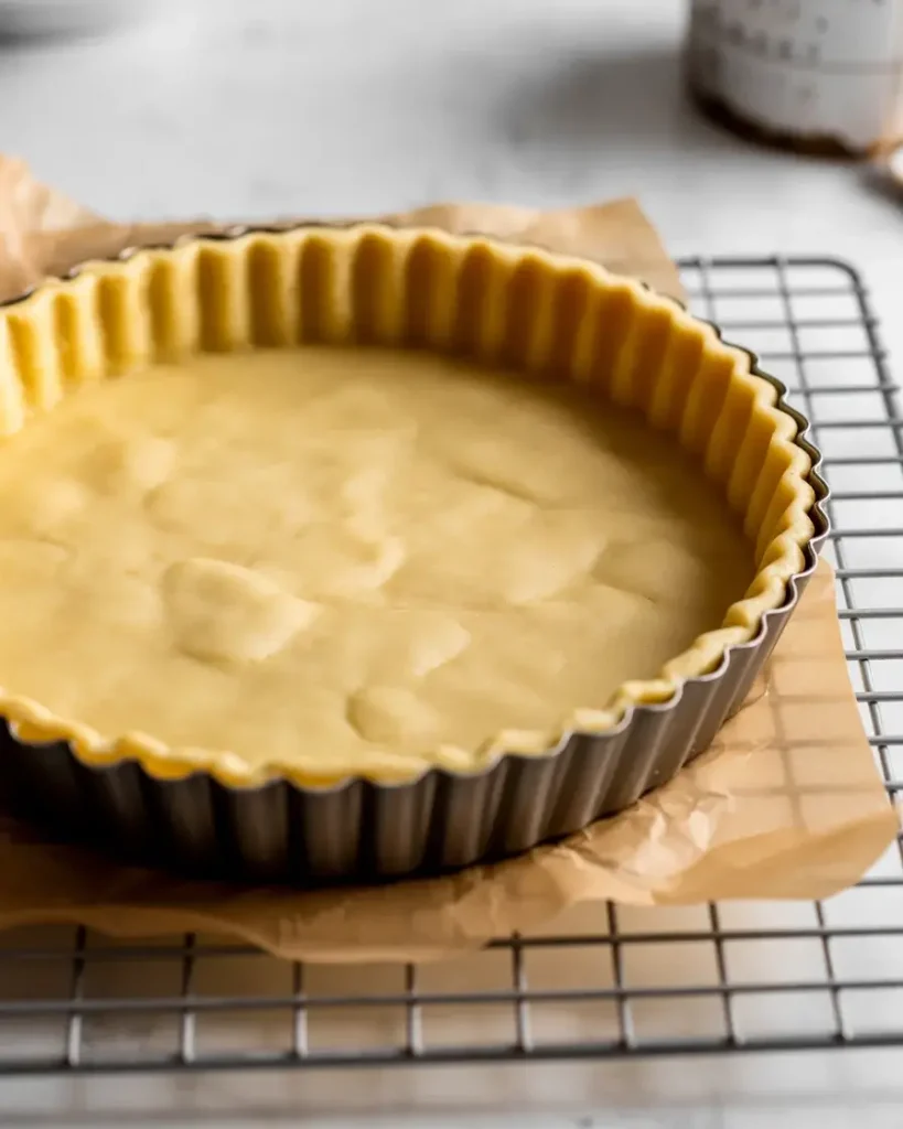 Blind-baked tart shell showing the dry, pale-gold base ready to hold the almond filling