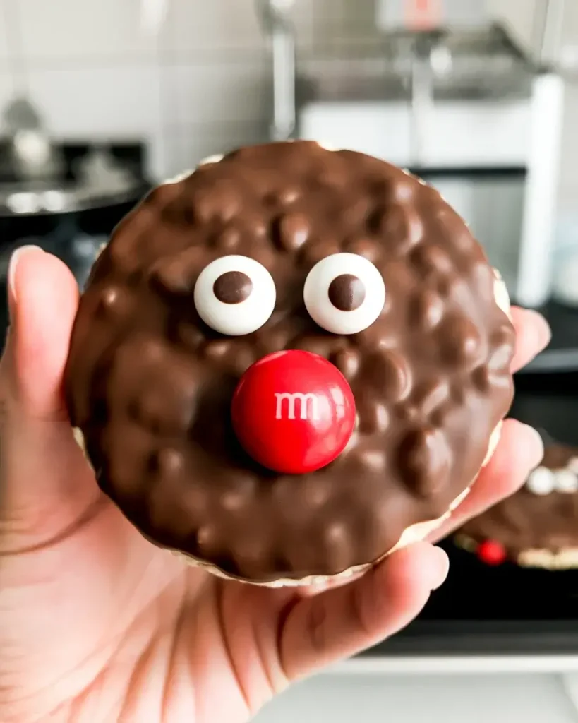 Pressing candy eyes and a red M&M nose into the chocolate reindeer face