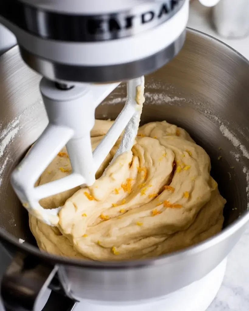 Shortbread dough just coming together with flour added, showing citrus zest throughout