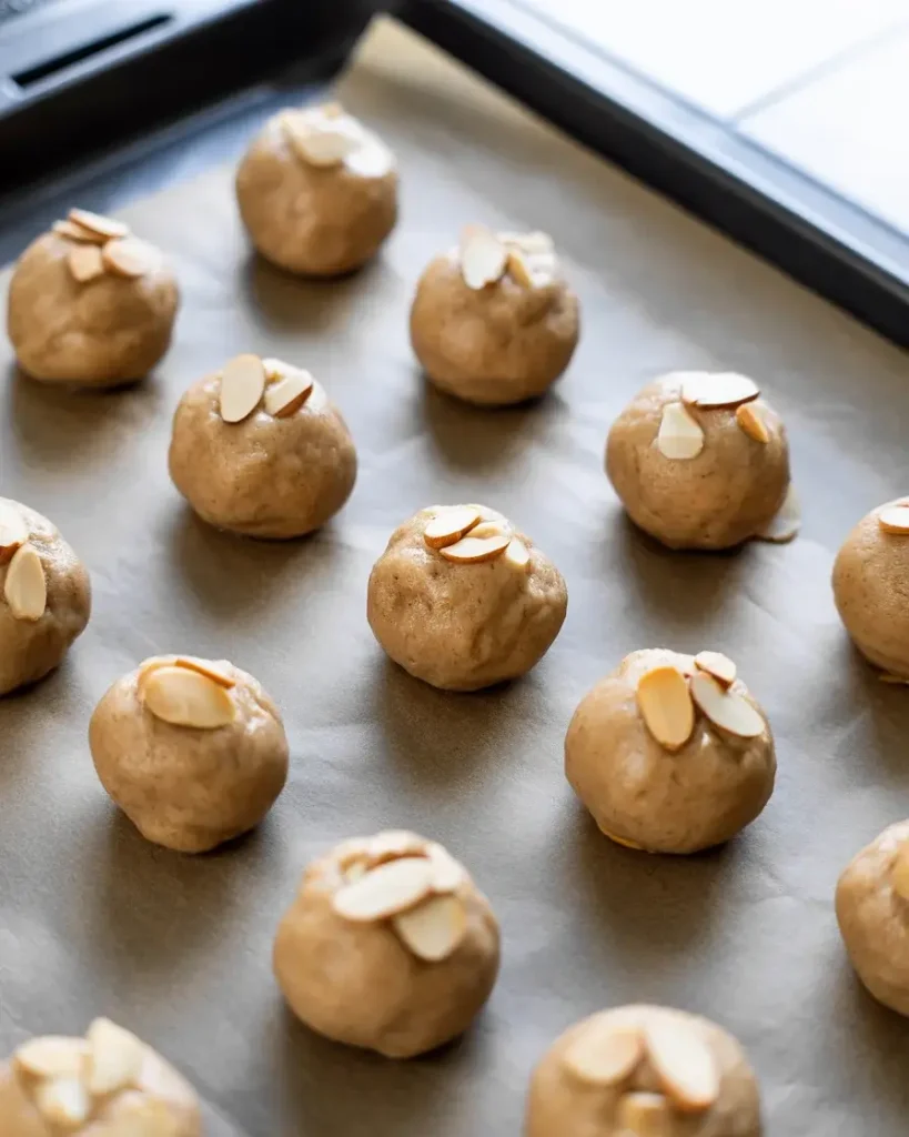 Chilled dough scooped and topped with almond slivers before baking