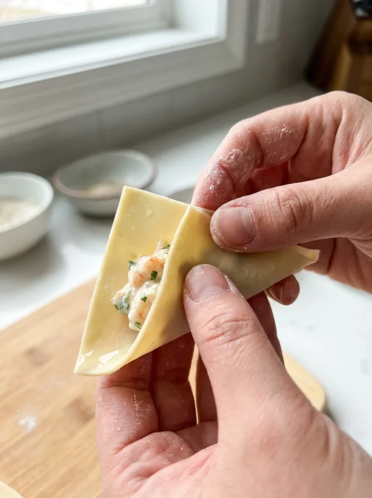 Fold wonton wrapper into a tight triangle, pressing out all air before sealing